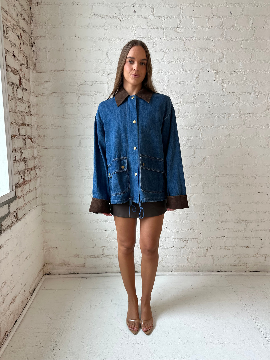 Woman wearing dark wash denim bomber jacket with brown corduroy collar and wrist cuffs.