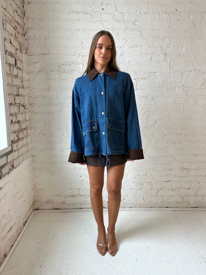 Woman wearing dark wash denim bomber jacket with brown corduroy collar and wrist cuffs.