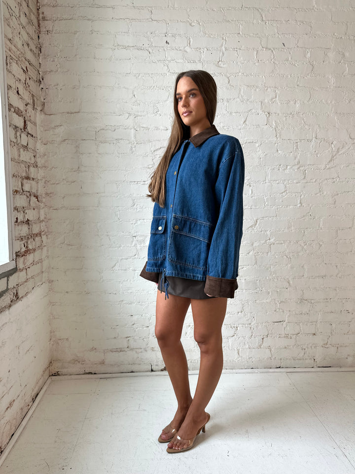 Woman wearing dark wash denim bomber jacket with brown corduroy collar and wrist cuffs.