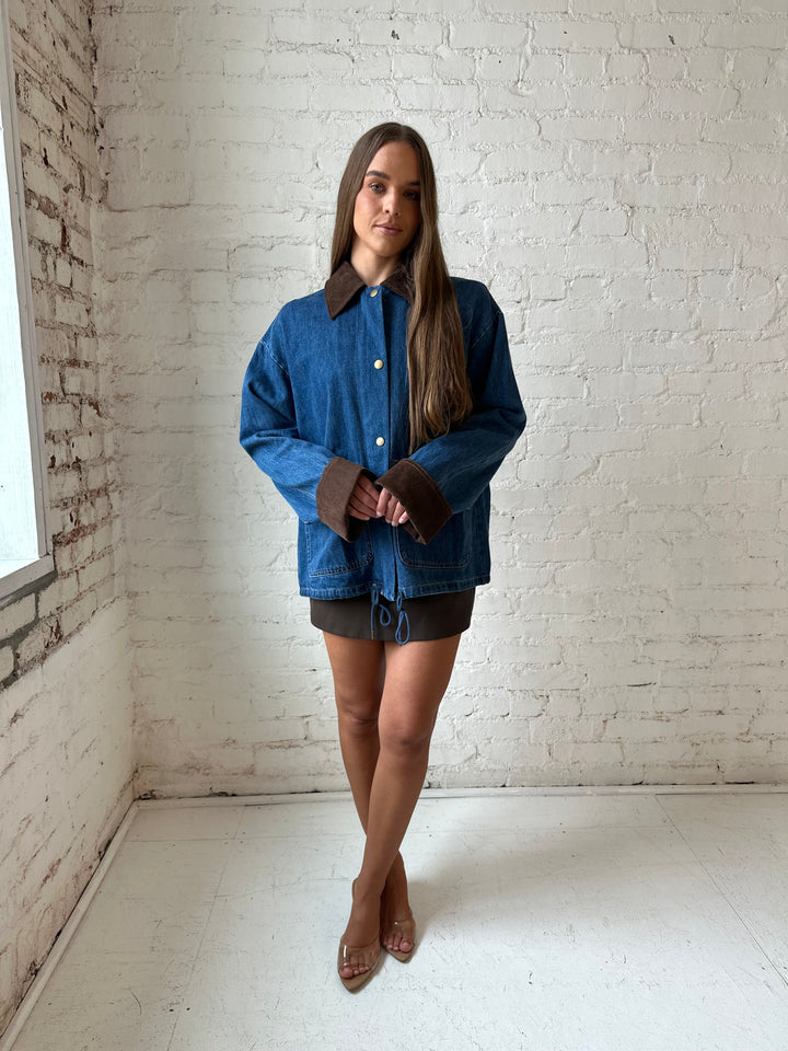 Woman wearing dark wash denim bomber jacket with brown corduroy collar and wrist cuffs.
