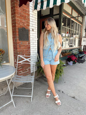 Woman in a light wash denim vest and matching high-waisted shorts set