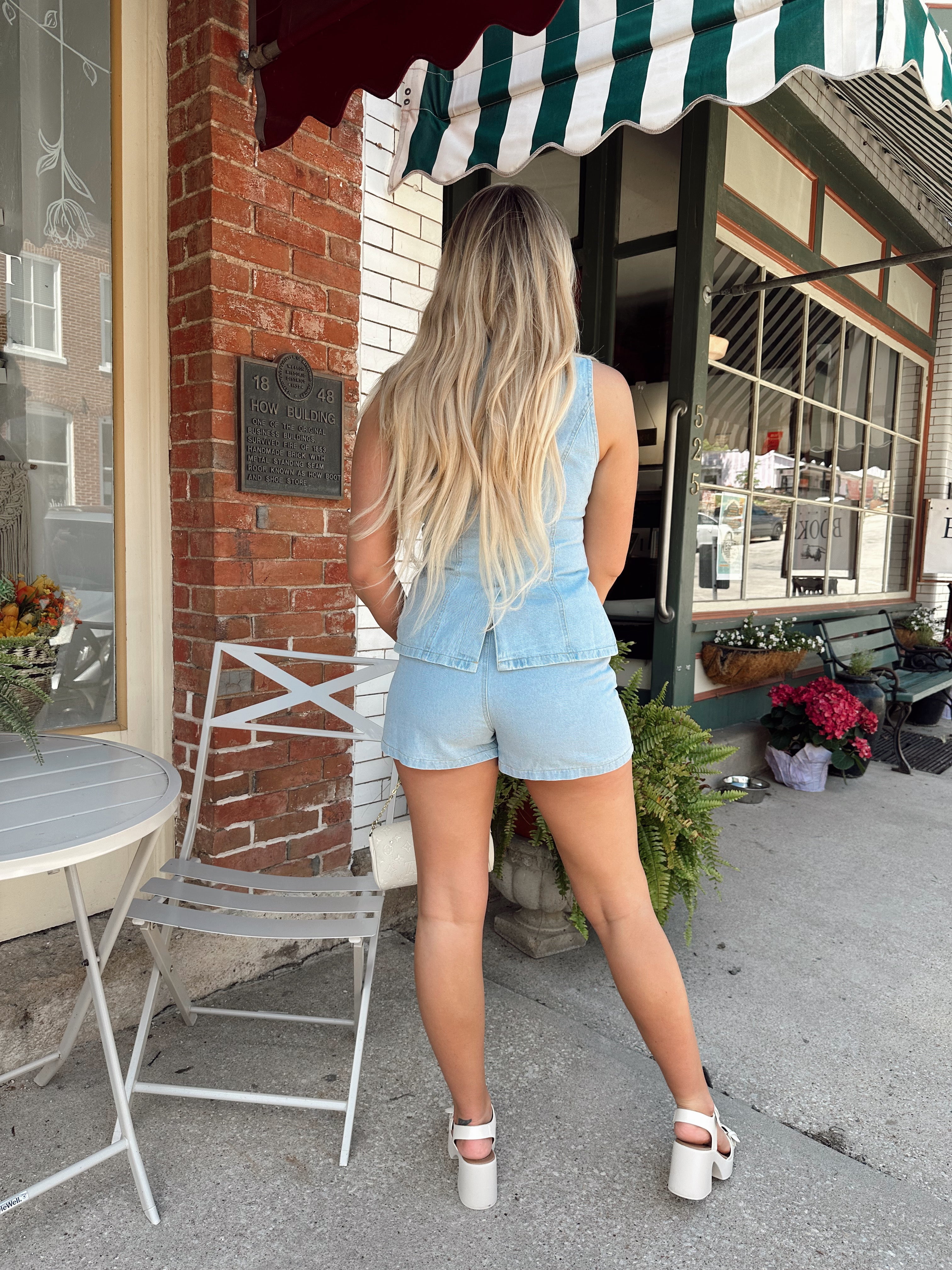 Woman in a light wash denim vest and matching high-waisted shorts set