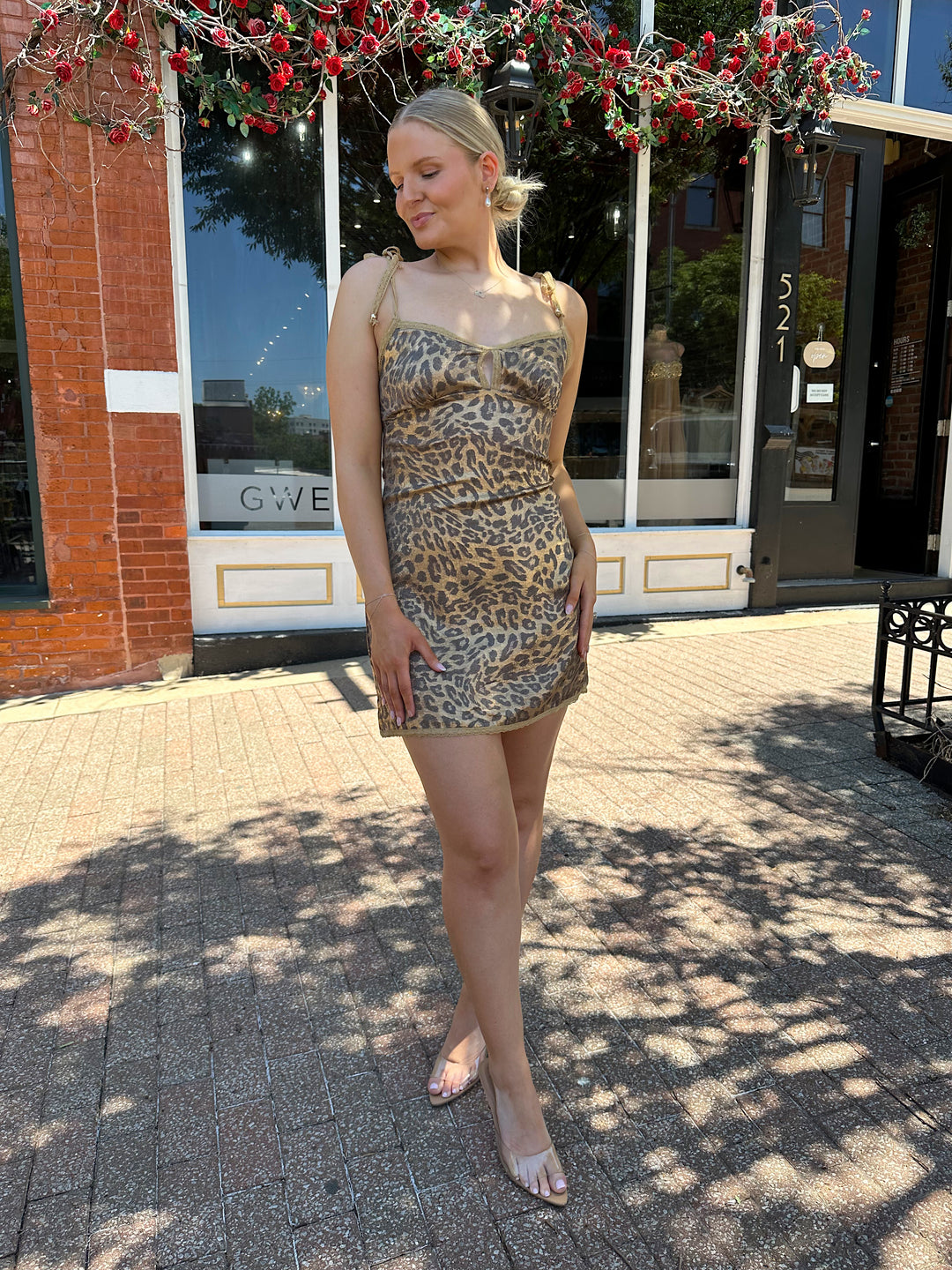 Woman wearing metallic cheetah print mini dress with lace tie straps, and lace trim detailing.
