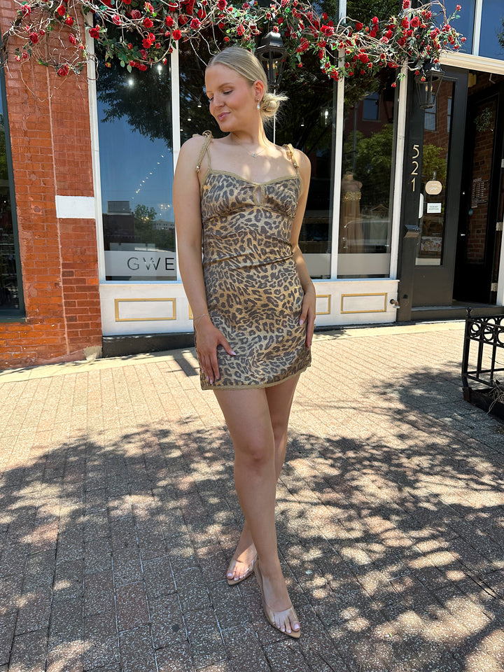 Woman wearing metallic cheetah print mini dress with lace tie straps, and lace trim detailing.