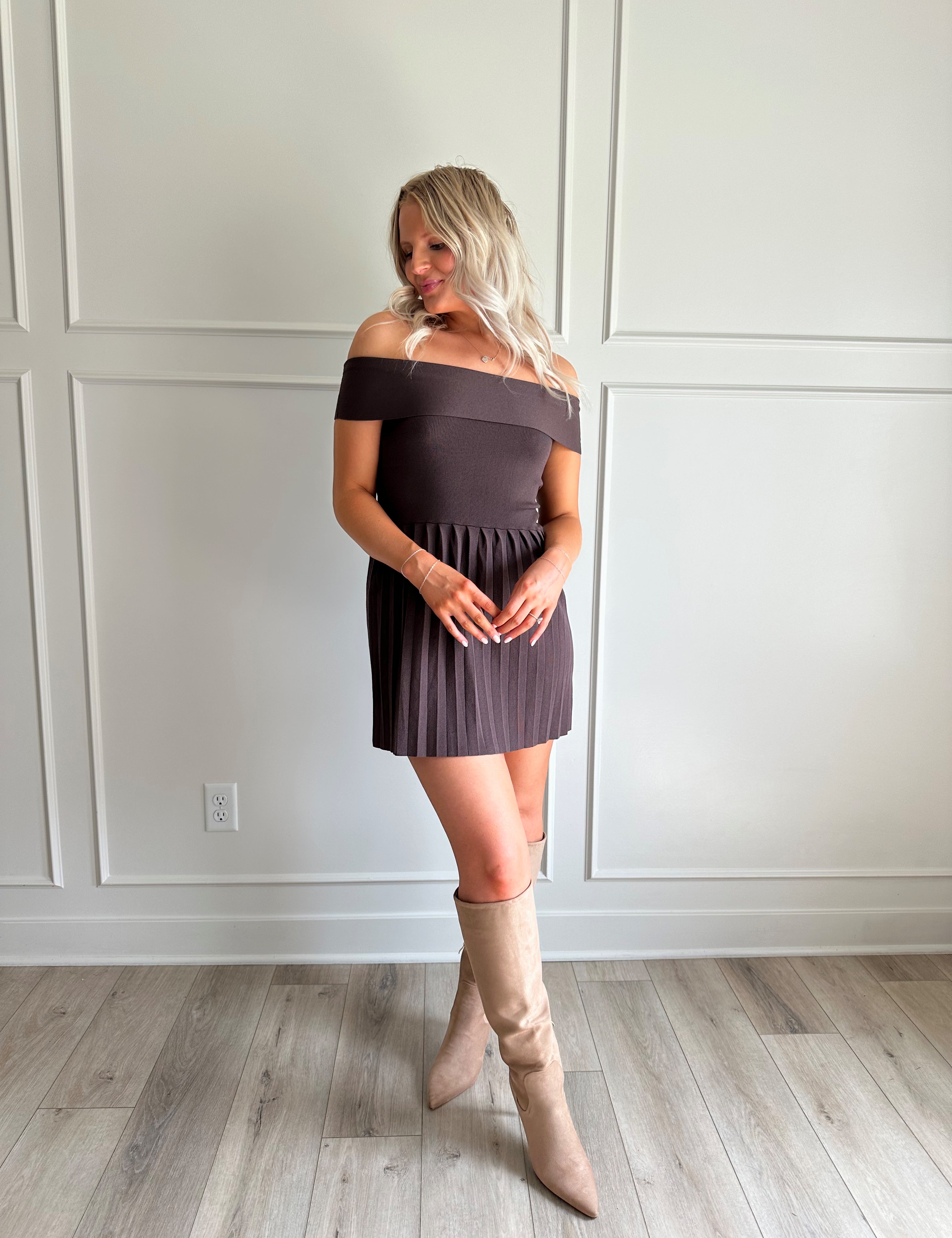Woman wearing brown knit off the shoulder mini dress with pleated mini dress.