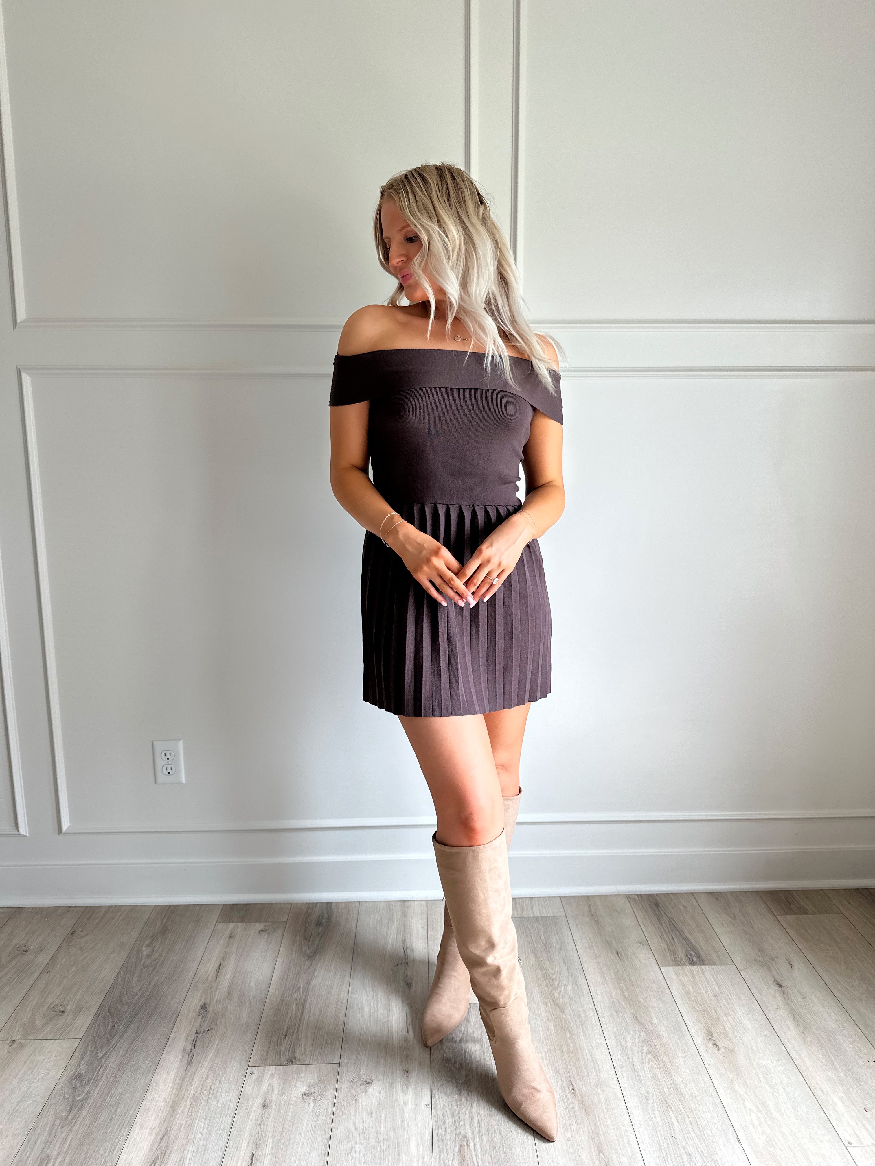 Woman wearing brown knit off the shoulder mini dress with pleated mini dress.