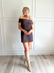 Woman wearing brown knit off the shoulder mini dress with pleated mini dress.