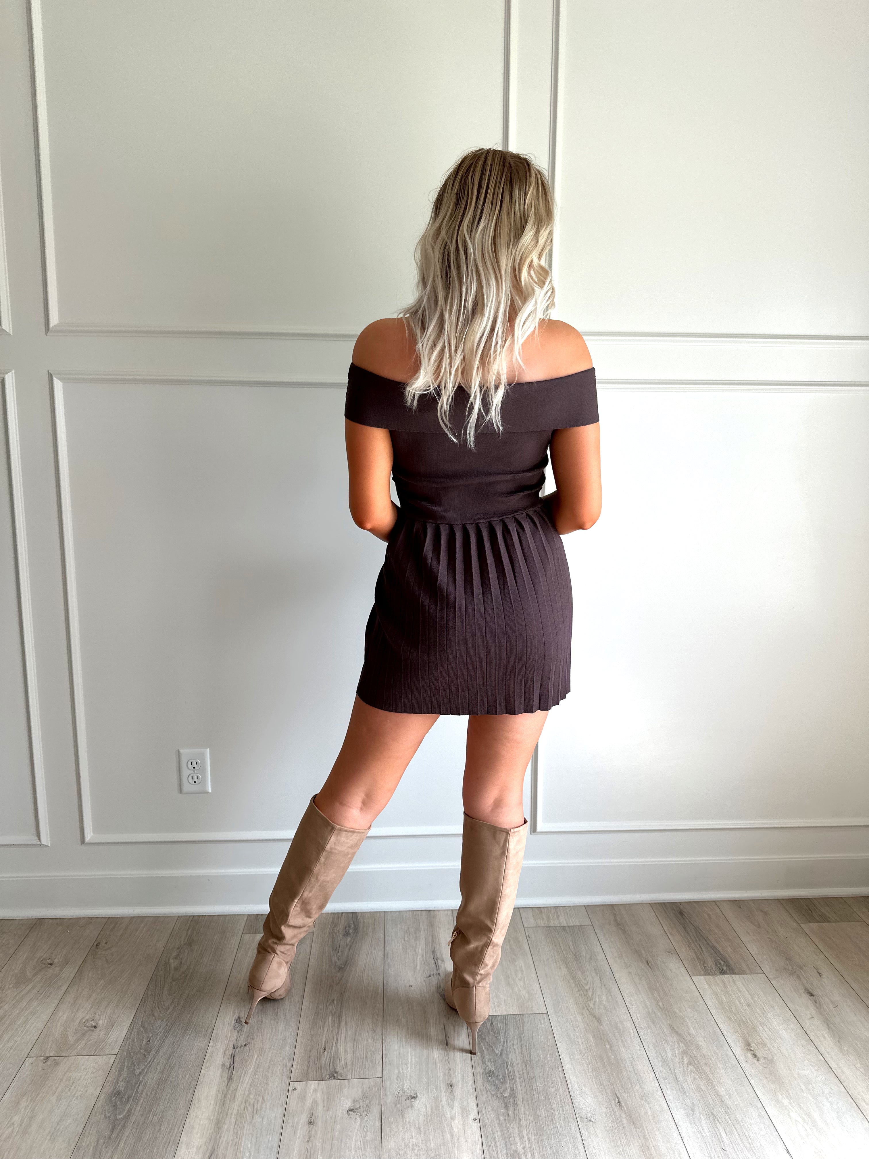 Woman wearing brown knit off the shoulder mini dress with pleated mini dress.