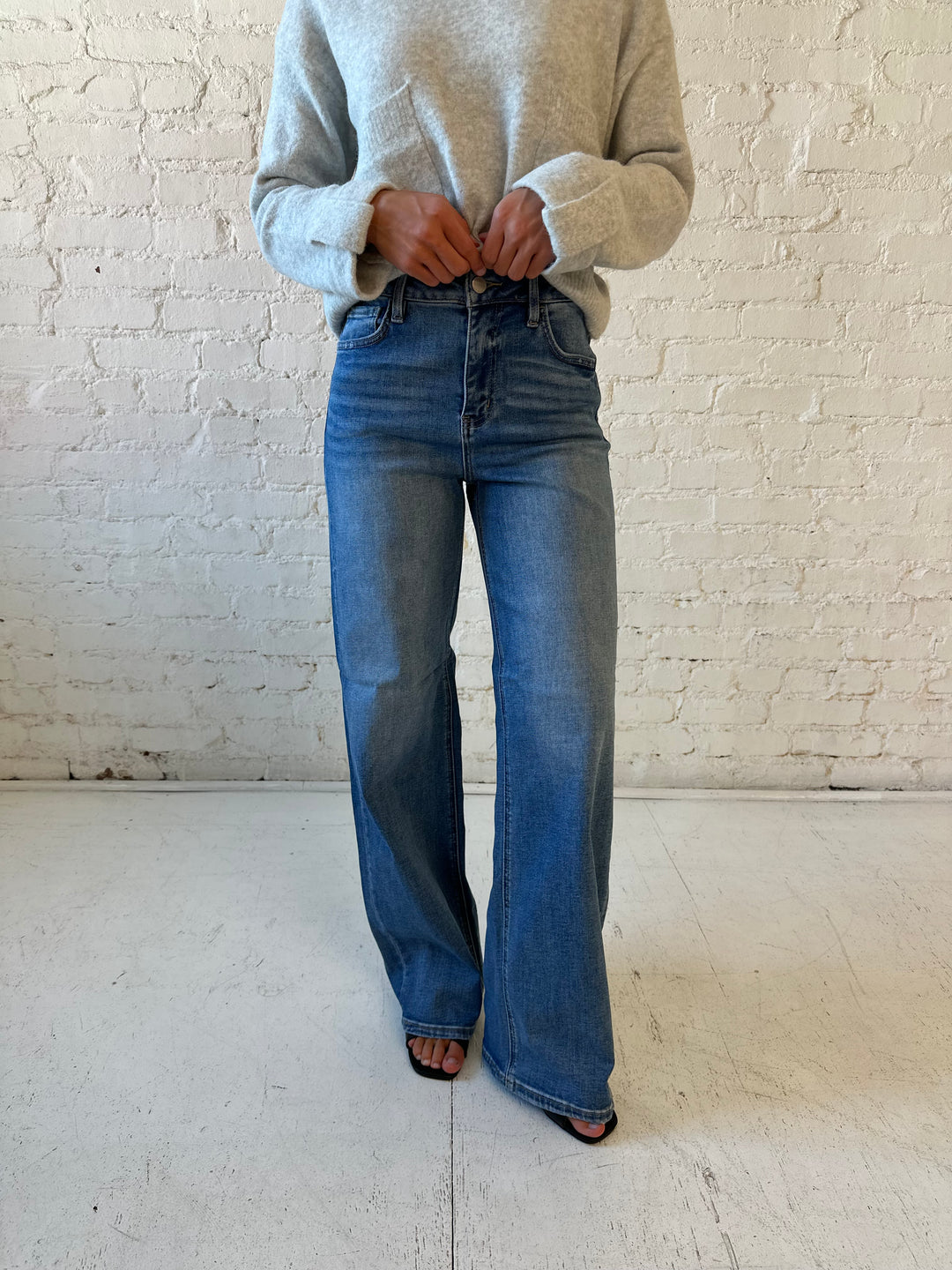 Woman wearing grey knit sweater with medium wash, wide leg jeans. 