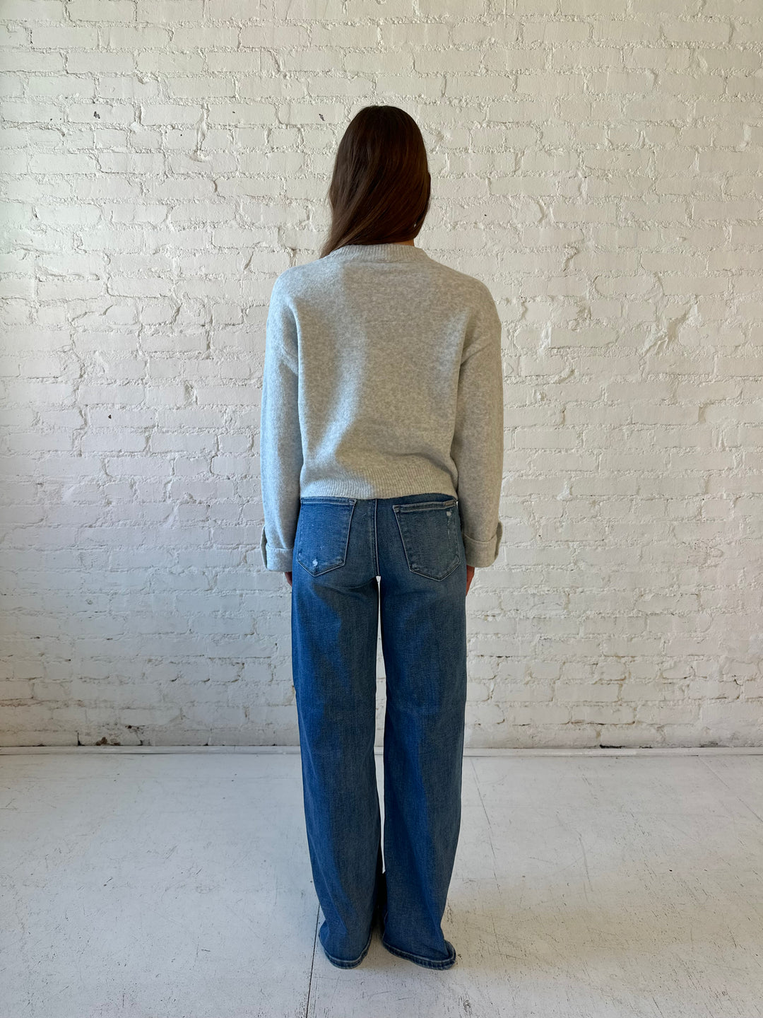 Woman wearing grey knit sweater with medium wash, wide leg jeans. 