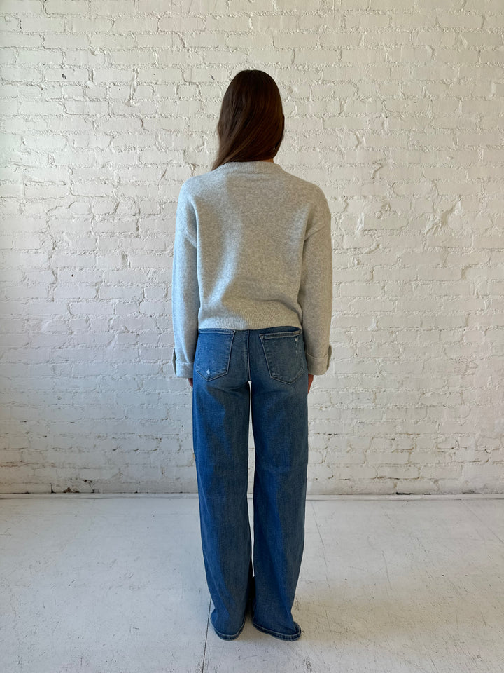 Woman wearing grey knit sweater with medium wash, wide leg jeans. 