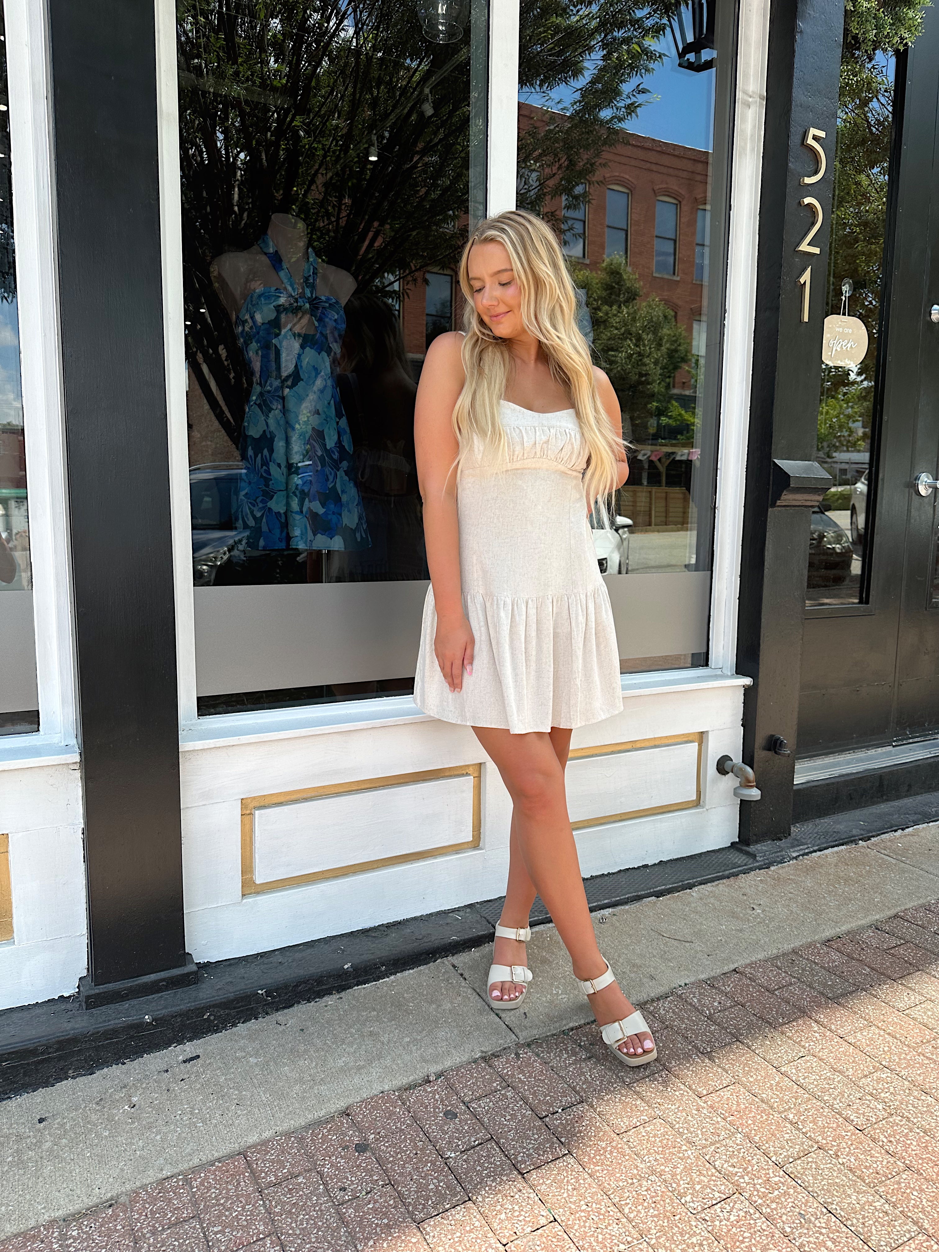 Neutral linen mini dress with drop waist and open back.