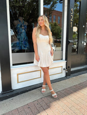 Neutral linen mini dress with drop waist and open back.