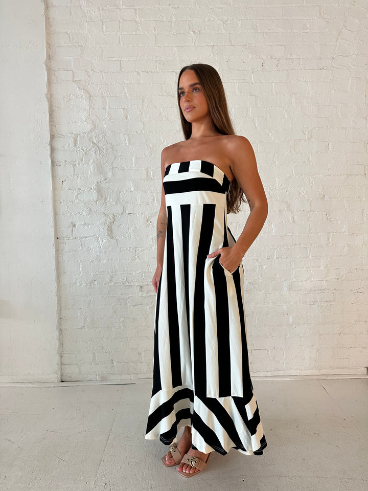 Woman wearing black and white striped, strapless midi dress with cutout back.