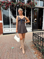 Woman wearing navy plaid bubble mini dress with white cardigan. 