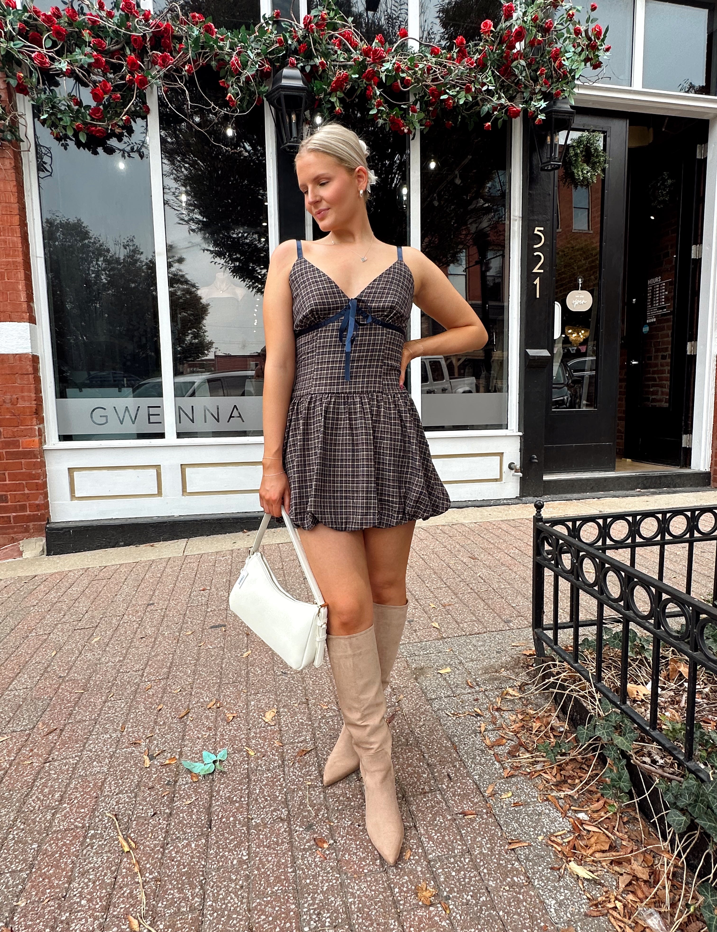 Woman wearing navy plaid bubble mini dress with white cardigan. 