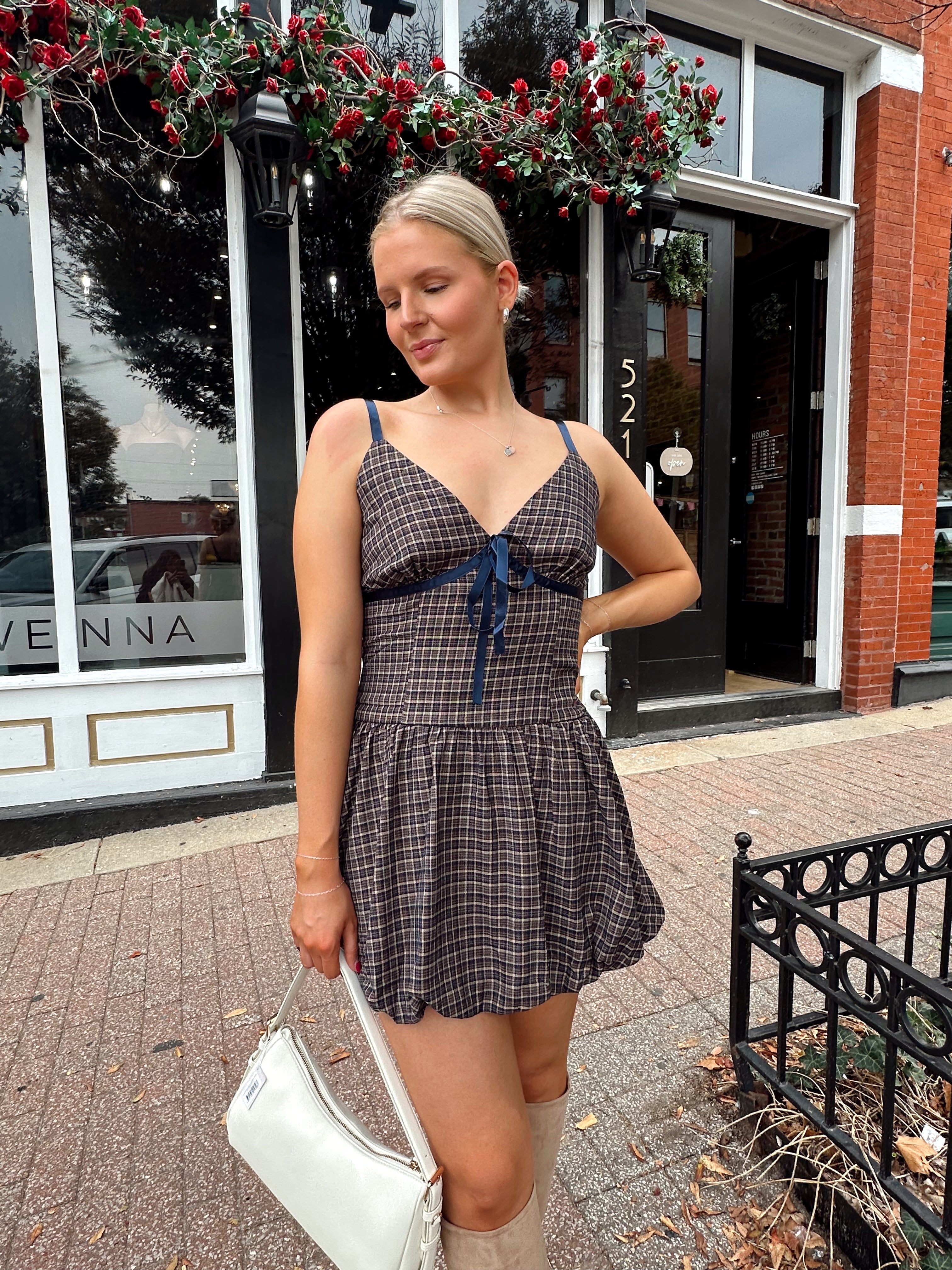 Woman wearing navy plaid bubble mini dress with white cardigan. 