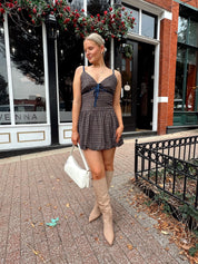 Woman wearing navy plaid bubble mini dress with white cardigan. 