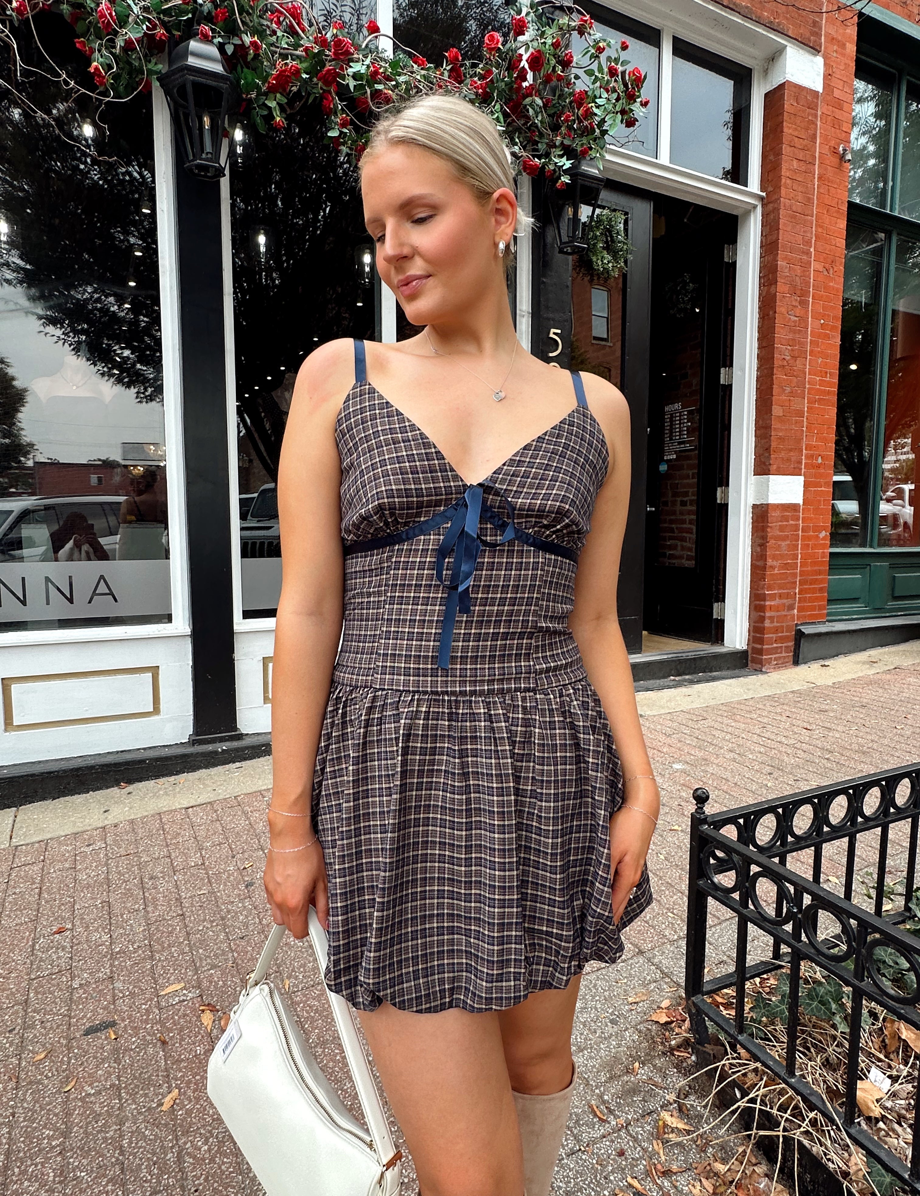 Woman wearing navy plaid bubble mini dress with white cardigan. 