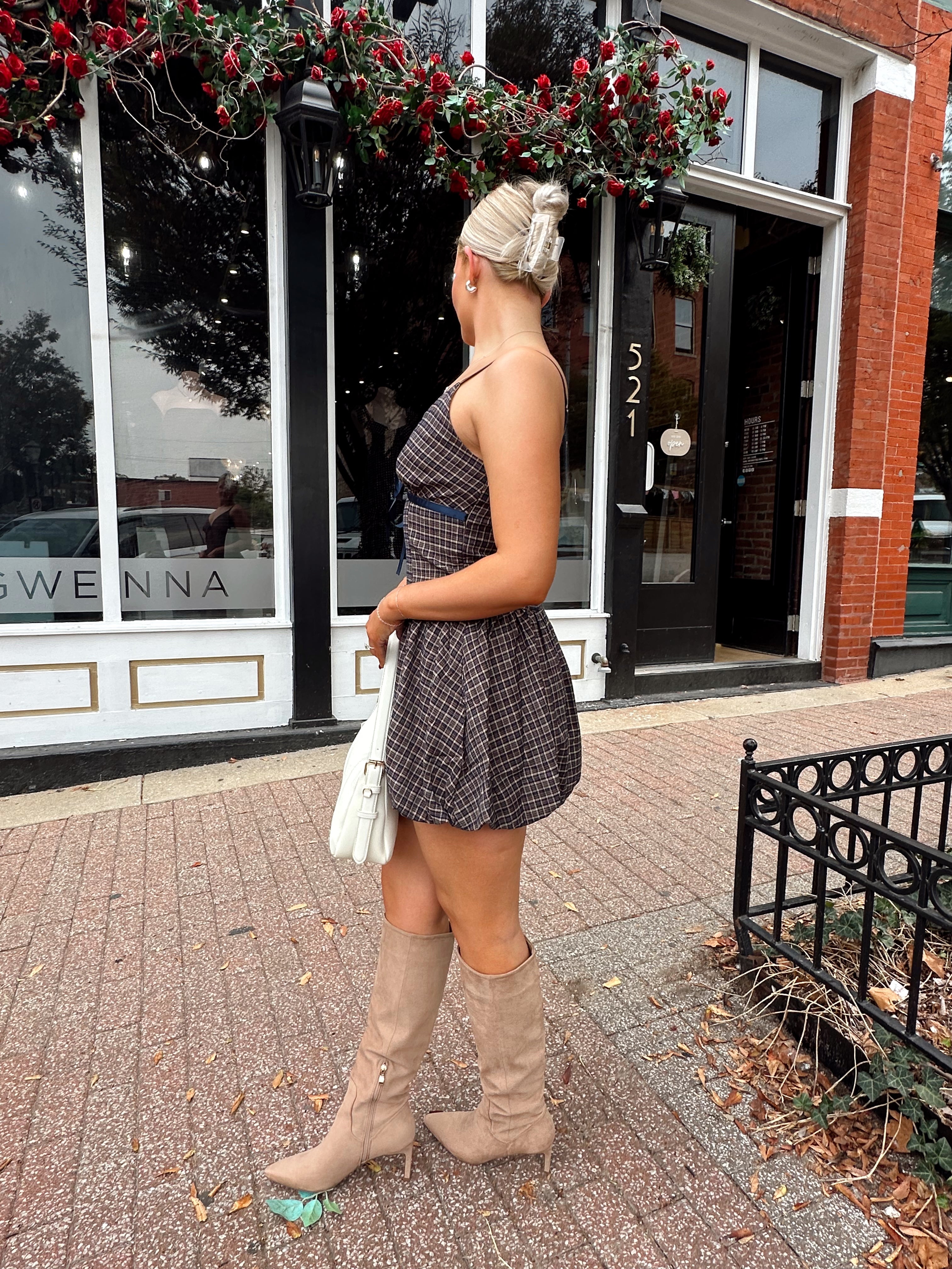 Woman wearing navy plaid bubble mini dress with white cardigan. 