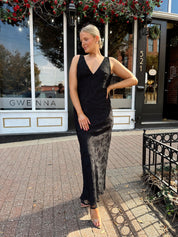 Woman wearing black textured midi dress with criss-cross cowl back. 