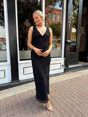 Woman wearing black textured midi dress with criss-cross cowl back. 