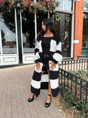 Woman wearing black and white striped knit long cardigan with black top and leather shorts.