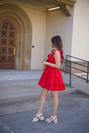 Kerry Tiered Mini Dress in red with a plunging neckline and tiered ruffles, twirling in front of an arched doorway.