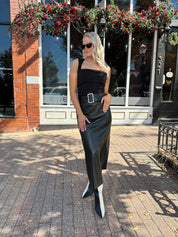 Woman wearing black leather belted midi skirt with black square neck top.