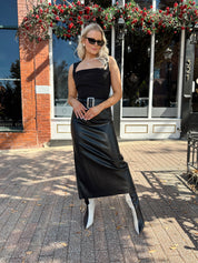Woman wearing black leather belted midi skirt with black square neck top.