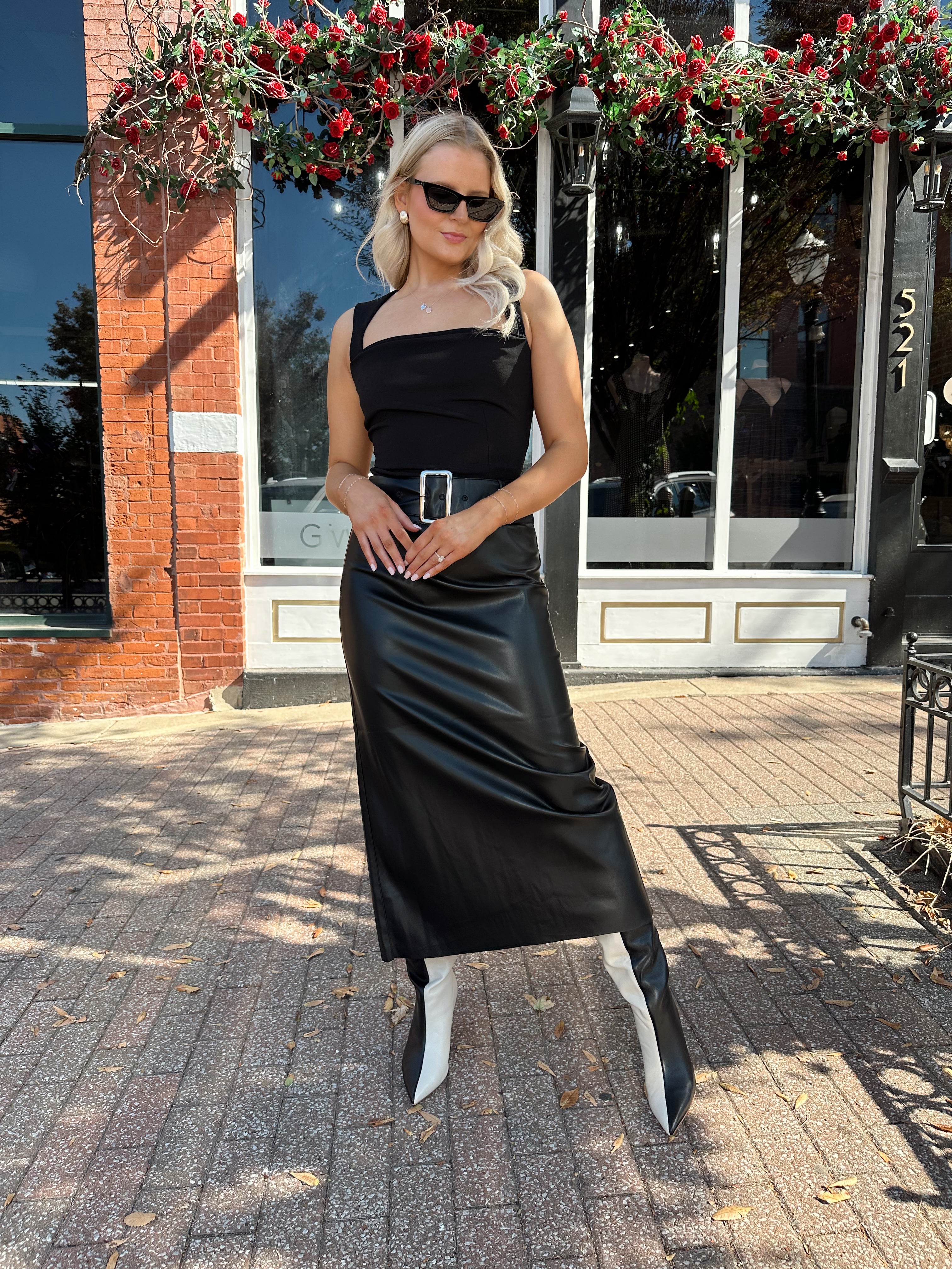 Woman wearing black leather belted midi skirt with black square neck top.