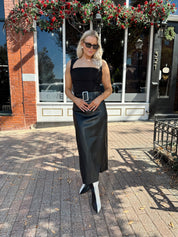 Woman wearing black leather belted midi skirt with black square neck top.