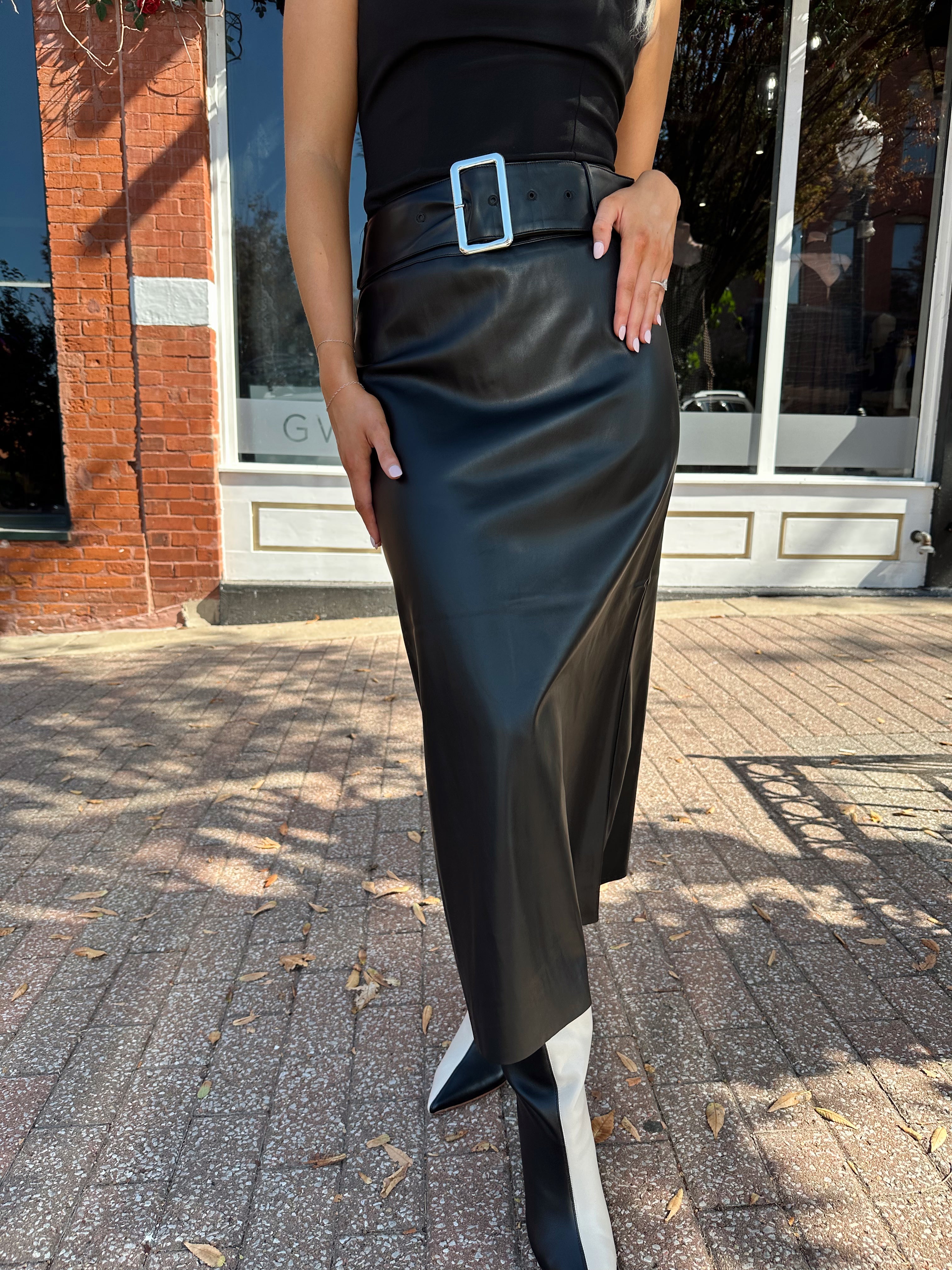Woman wearing black leather belted midi skirt with black square neck top.