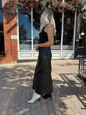 Woman wearing black leather belted midi skirt with black square neck top.