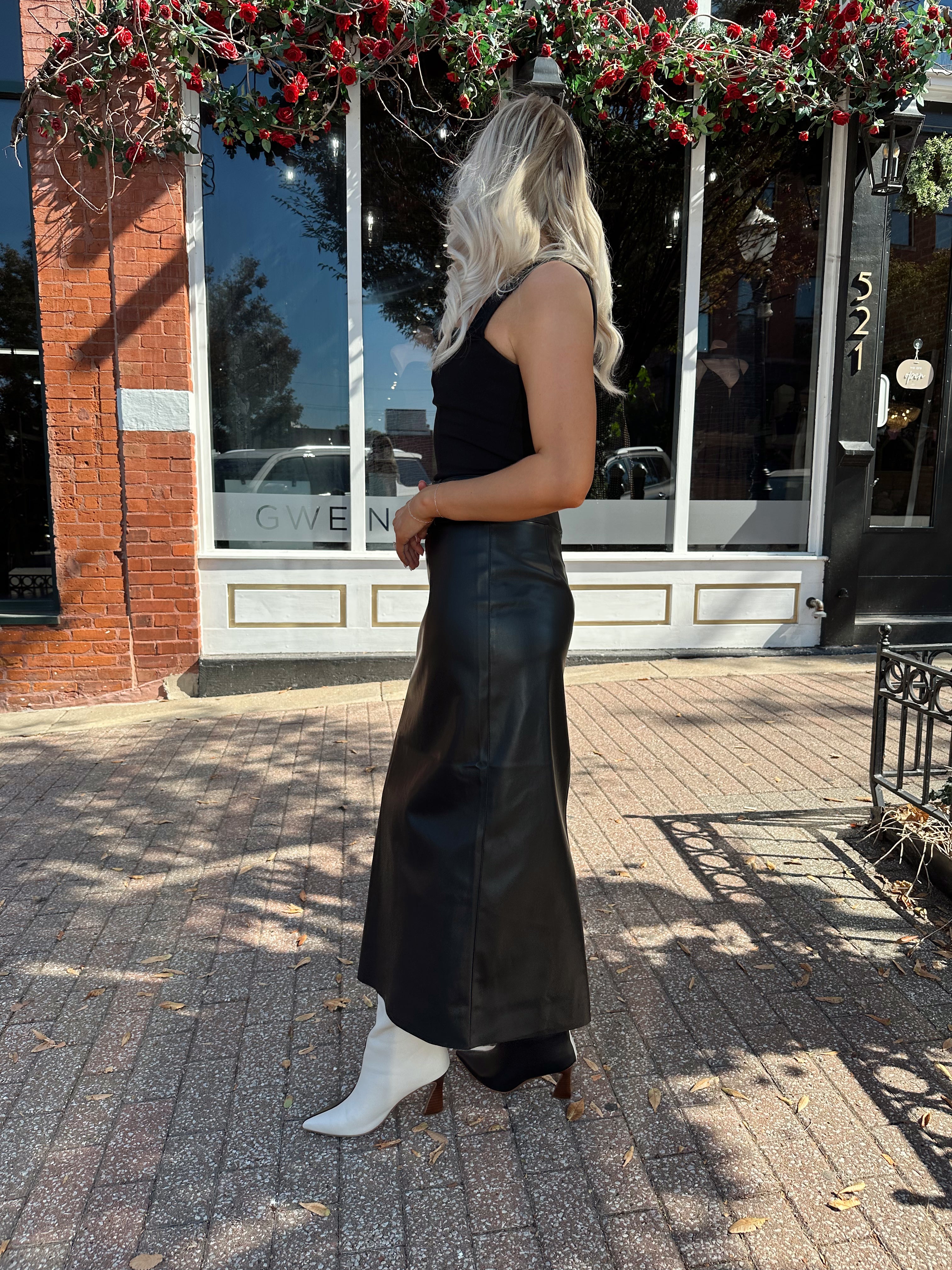Woman wearing black leather belted midi skirt with black square neck top.