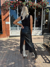 Woman wearing black leather belted midi skirt with black square neck top.
