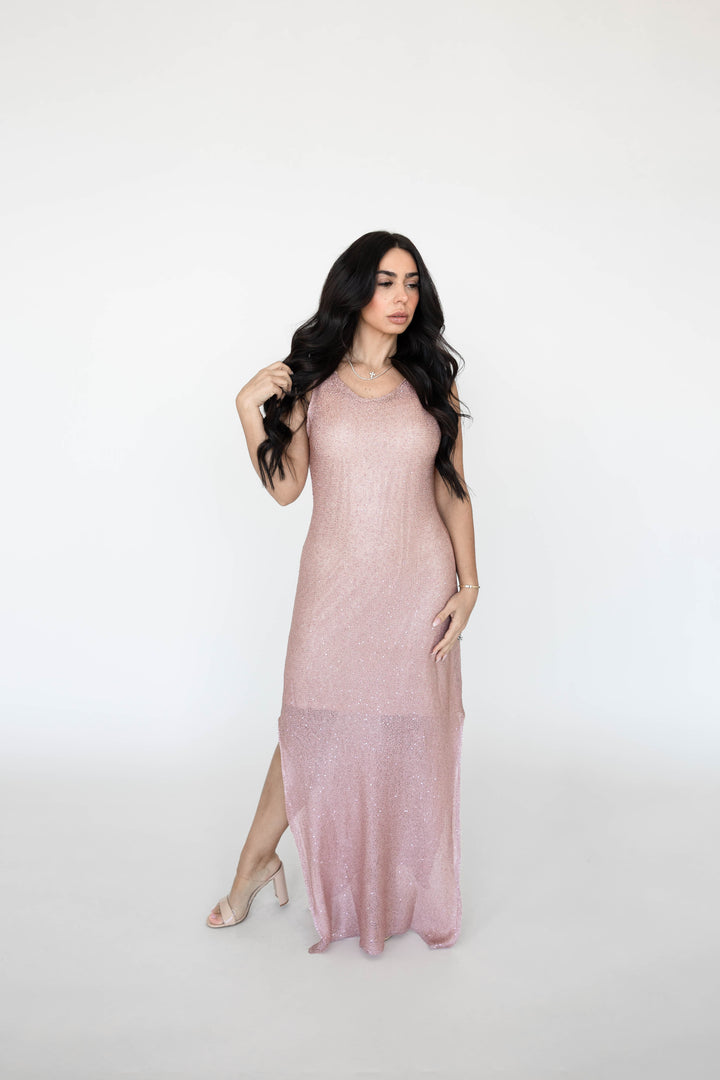 Woman wearing a sheer blush shimmer maxi dress with slit up the side.