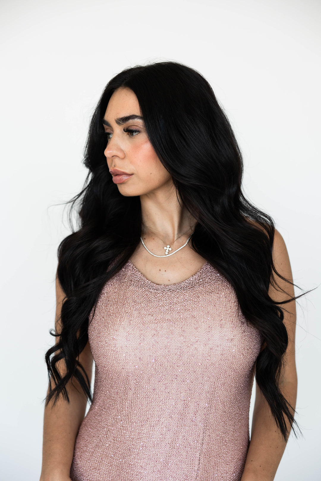 Woman wearing a sheer blush shimmer maxi dress with slit up the side. 