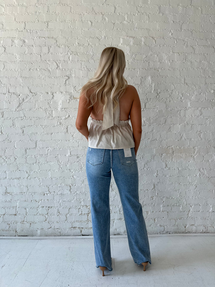 Woman wearing high waisted distressed jeans with striped halter top.