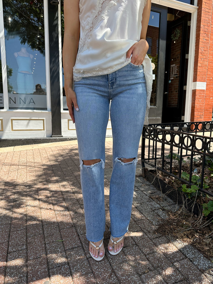 Woman wearing high rise distress jean with raw hem. 