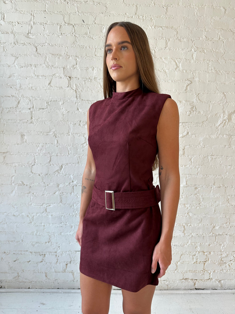 Woman wearing burgundy suede mini dress with belted waist. 