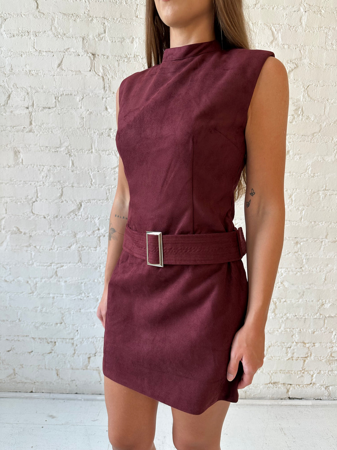 Woman wearing burgundy suede mini dress with belted waist. 