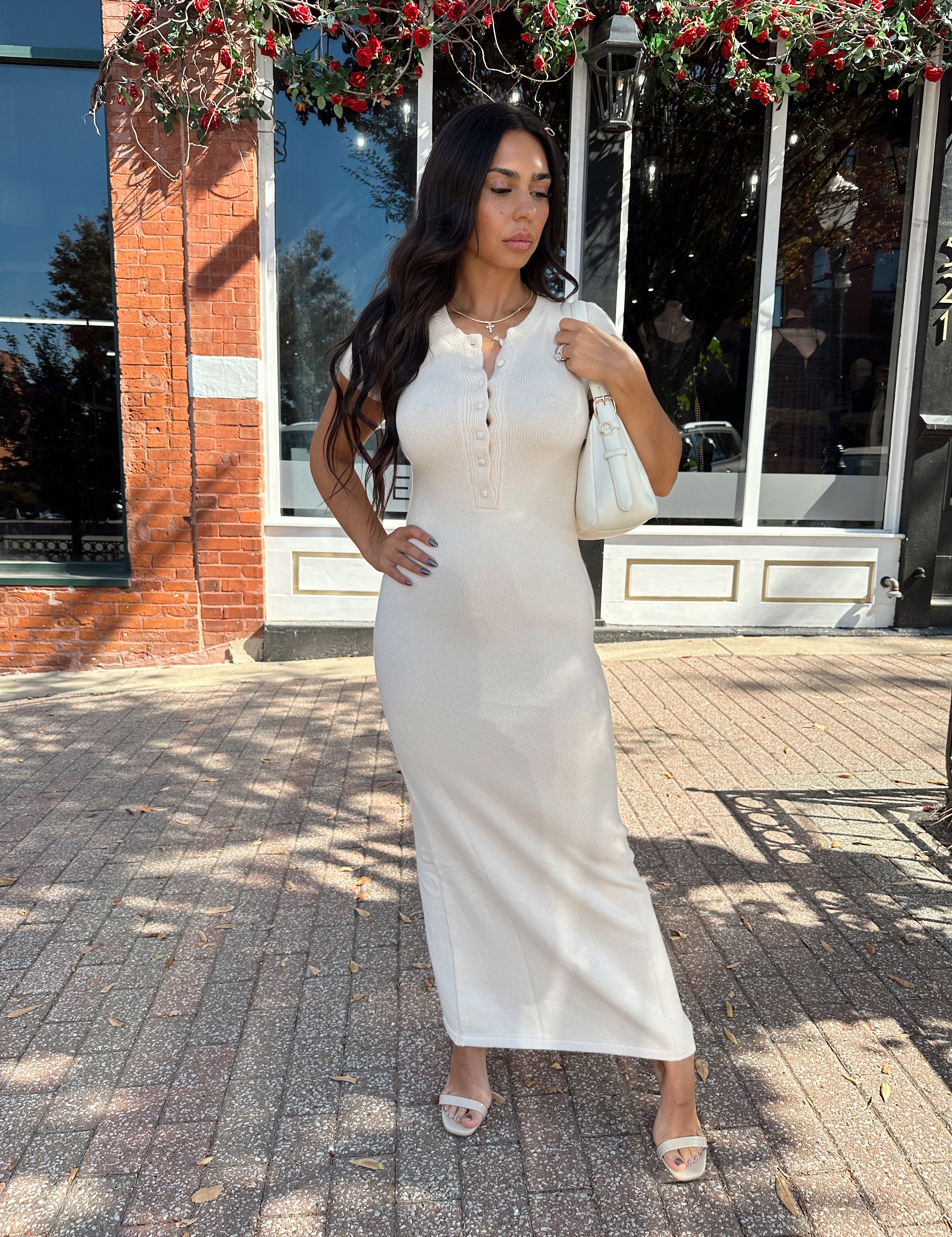 Woman wearing cream cap sleeve knit midi dress with button detailing.