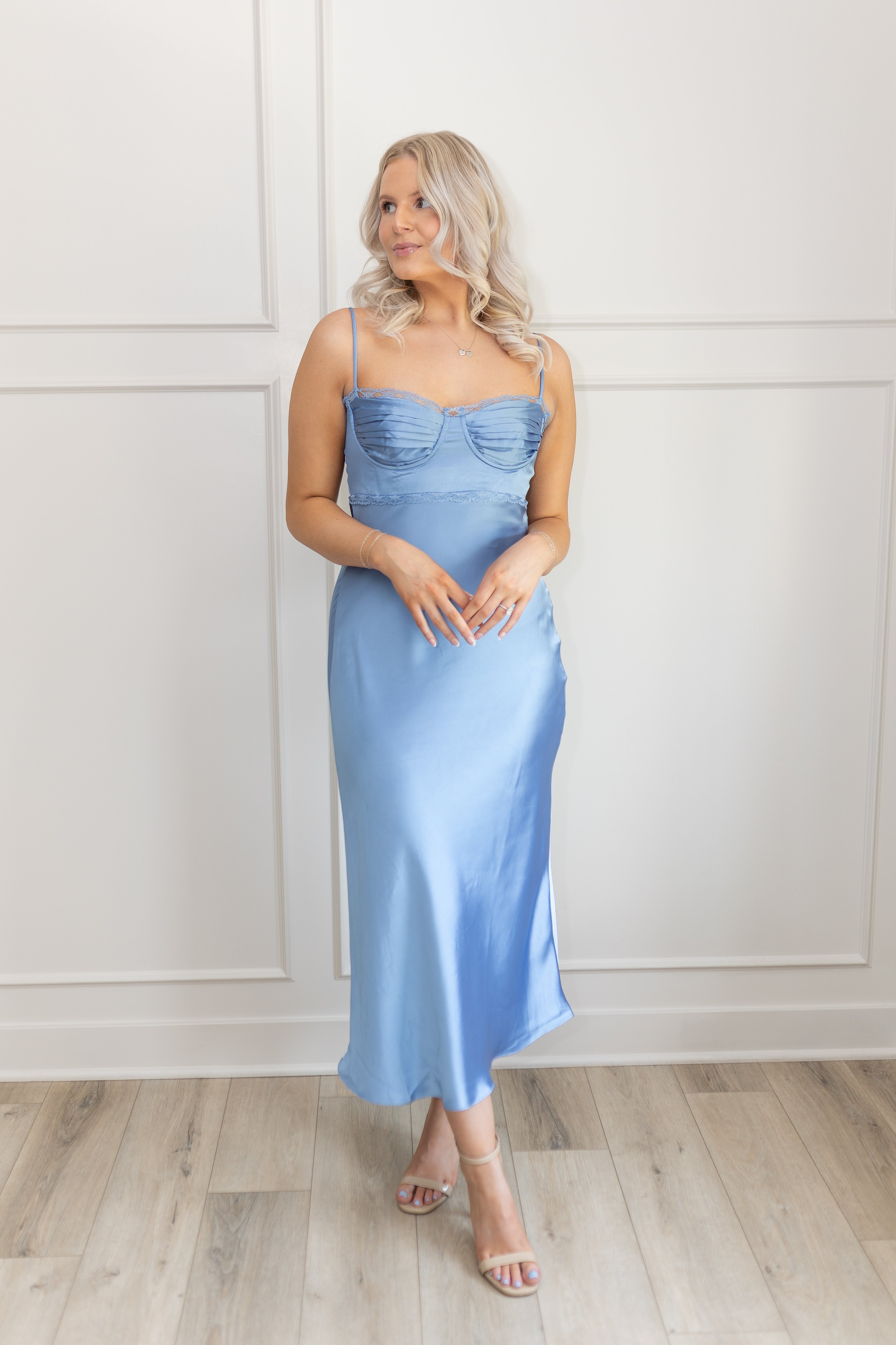 Model wearing dusty blue satin midi dress with bustier bodice and slit
