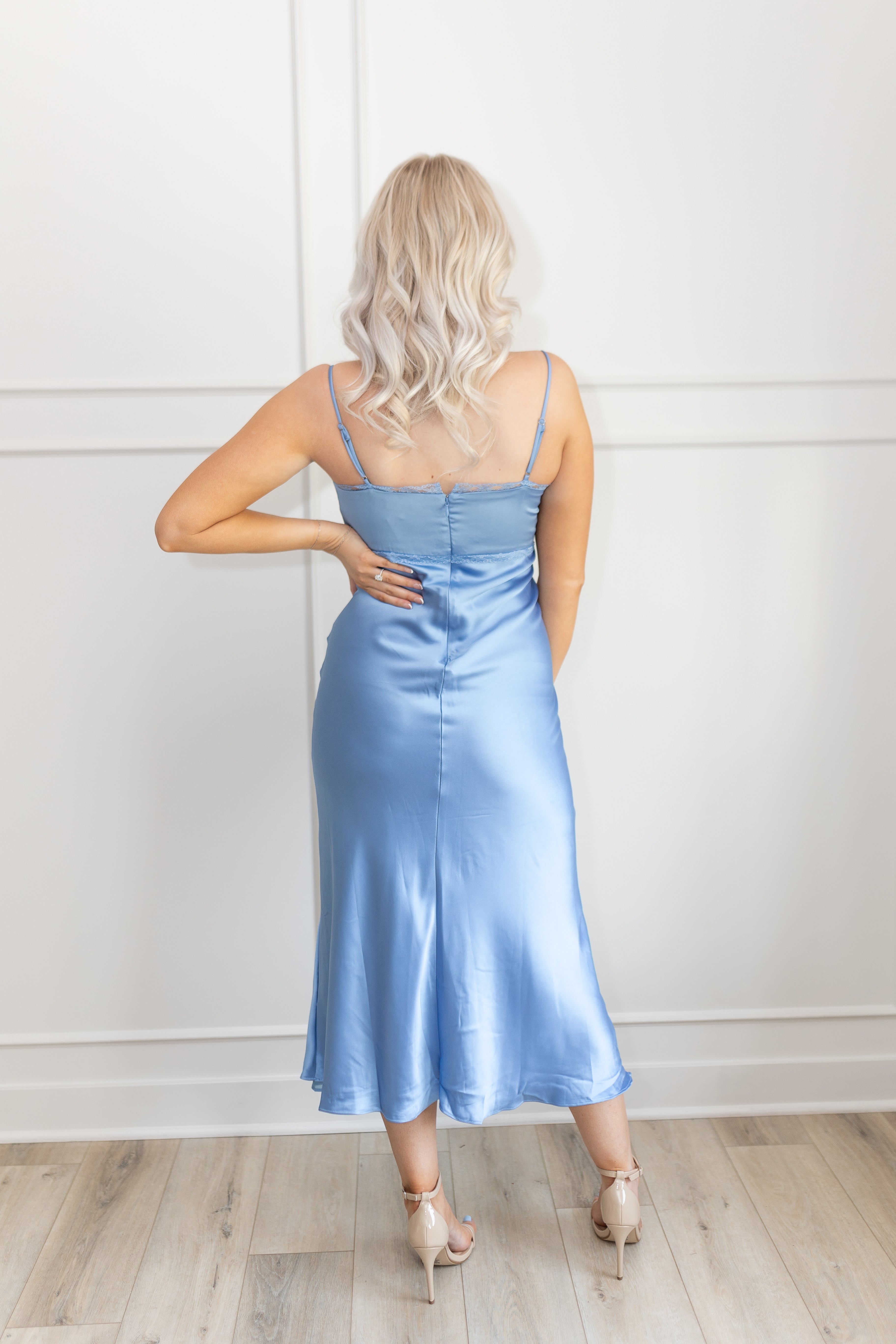 Model wearing dusty blue satin midi dress with bustier bodice and slit