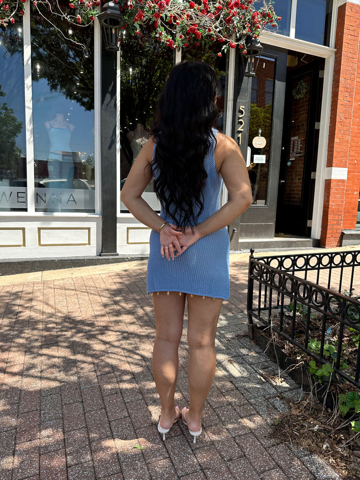 Woman wearing dusty blue knit mini dress with see shell detail on the trim.
