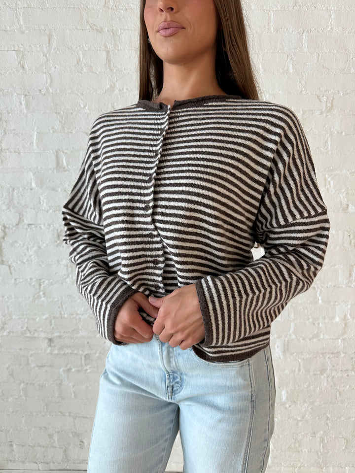 Woman wearing brown and cream striped knit cardigan with light wash barrel jeans. 