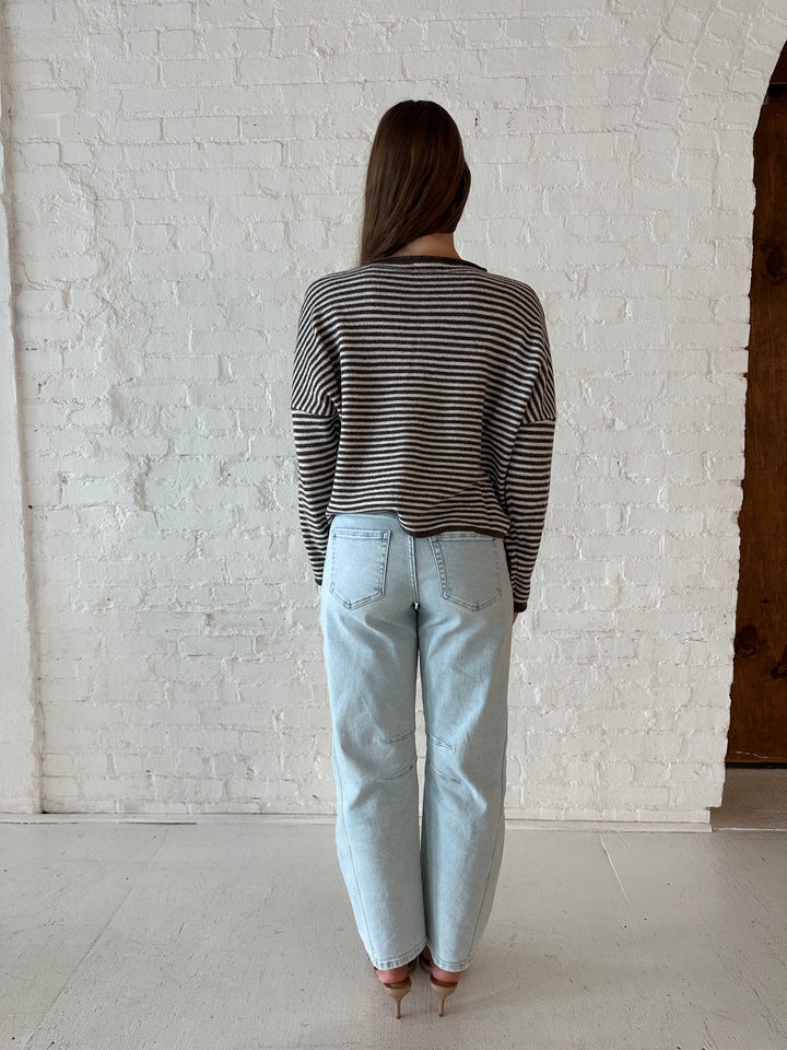 Woman wearing brown and cream striped knit cardigan with light wash barrel jeans. 
