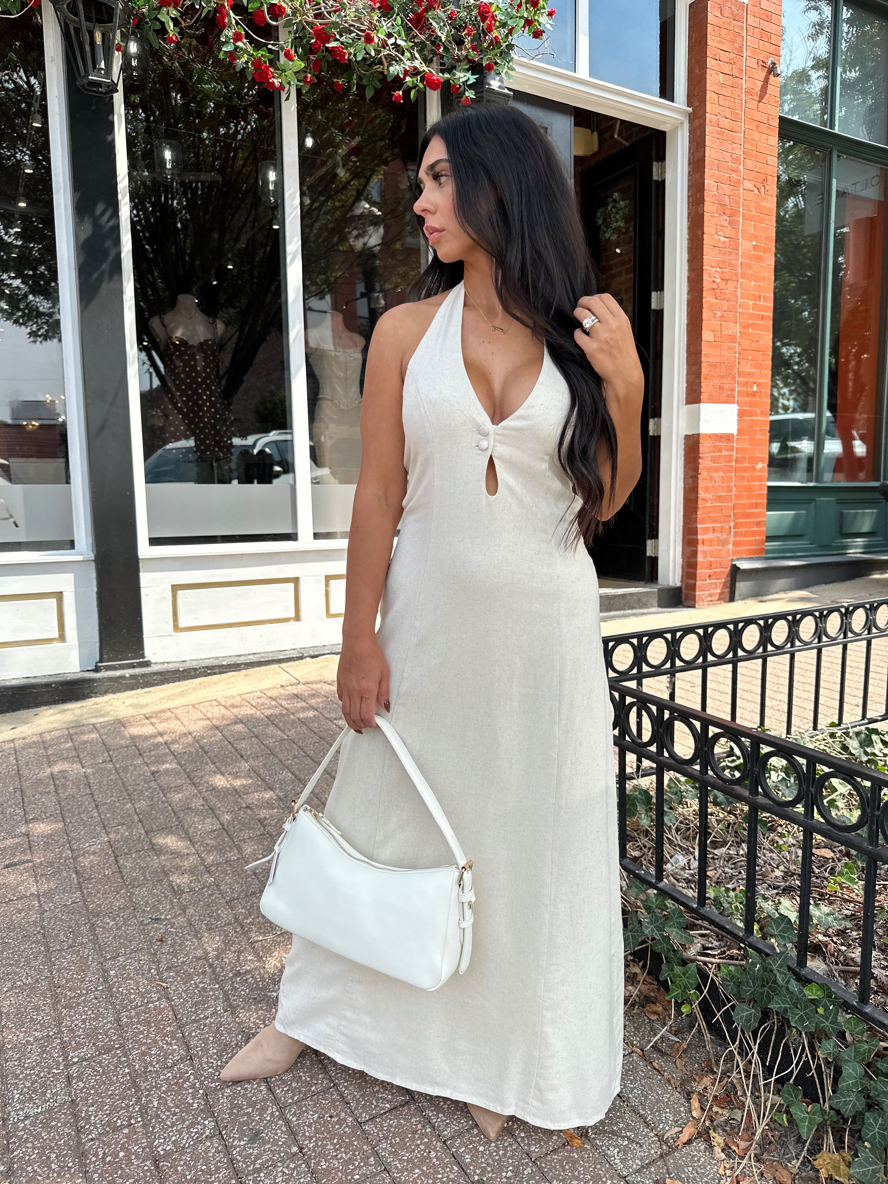 Woman wearing natural colored maxi dress with halter keyhole cutout neckline and tie back.