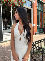 Woman wearing natural colored maxi dress with halter keyhole cutout neckline and tie back.